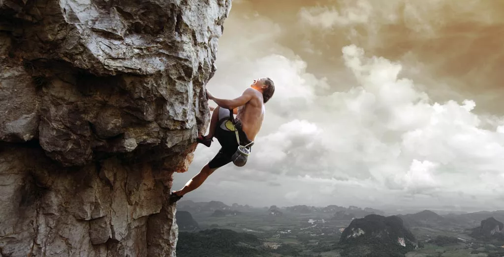 Young man climbing natural rocky wall as a Adventure Therapy​