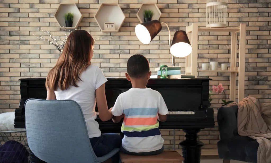 A boy with teacher learning to play piano at home