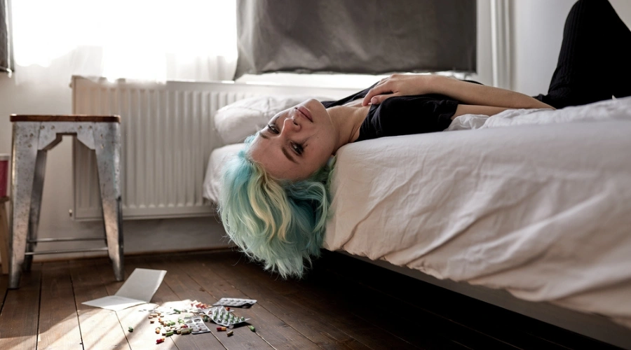 Women with head hanging down on bed displaying the common signs you may Be facing a Dual Diagnosis