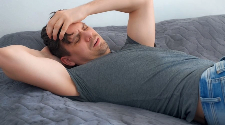 Man laying on bed displaying withdrawal symptoms of fentanyl