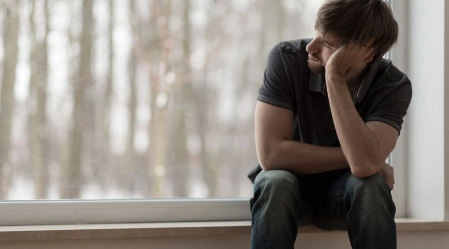 Man sitting looking outside the window displaying emotional relapse