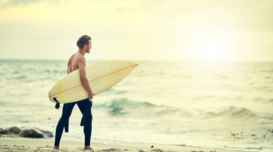 Image of a male with surfboard facing the ocean - South Shores Detox Uses a Holistic Approach