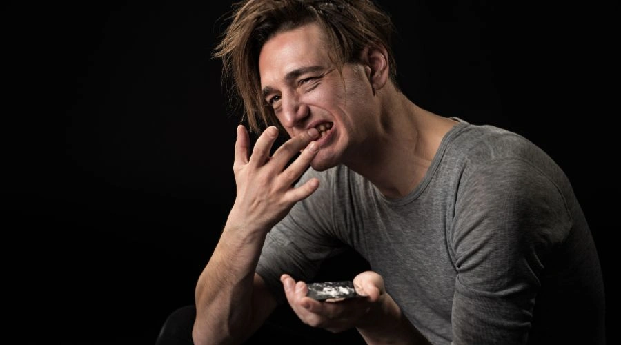 Image of Man in t-shirt rubbing gums with one finger -Why Do People Rub Their Gums with Cocaine