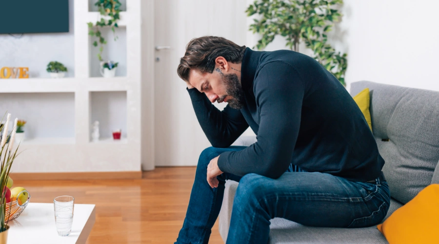 Image of a depressed man sitting on a sofa showing signs of ketamine abuse and emotional distress