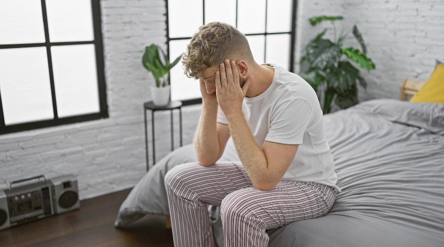 Image of a man sitting on the edge of his bed, showing signs of kratom dependence and substance use disorder
